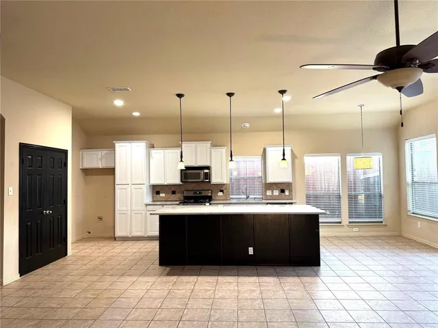 a kitchen with stainless steel appliances kitchen island granite countertop a sink and a cabinets