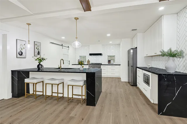 a kitchen with stainless steel appliances kitchen island a refrigerator and a wooden cabinets