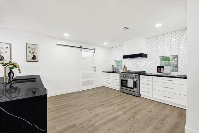 a kitchen with granite countertop a sink cabinets stainless steel appliances and a window