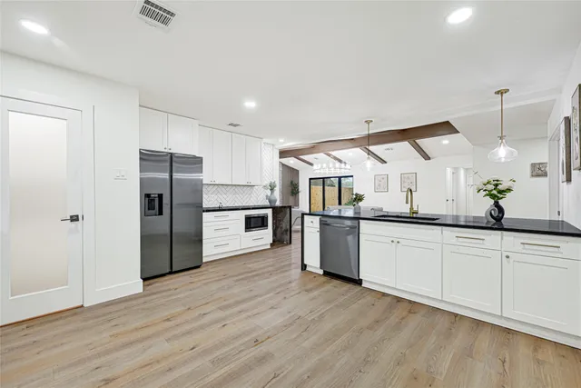 a large kitchen with a center island wooden floor and stainless steel appliances