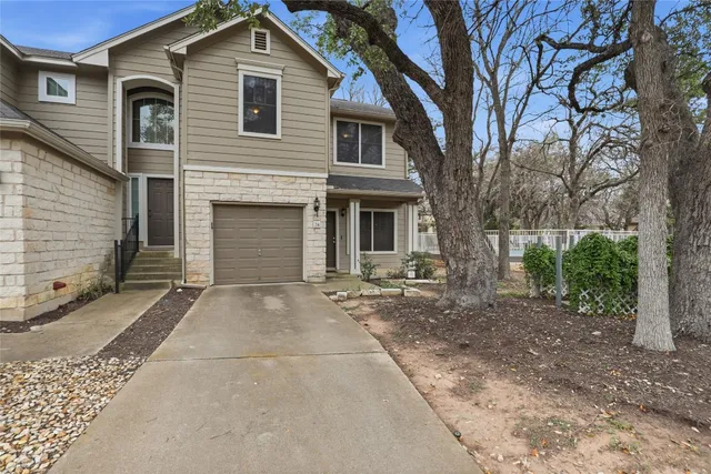 a view of a house with a yard and large tree