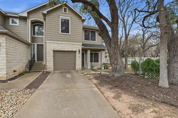 a view of a house with a yard and large tree
