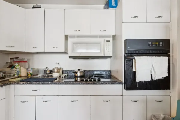 a kitchen with white cabinets and appliances