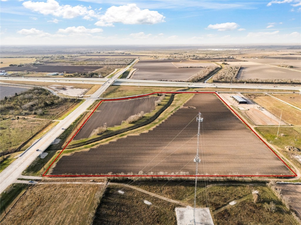 Expansive plot of land outlined in red, located near major roads and highways. Ideal for development with open fields and clear skies, offering vast potential for building projects.