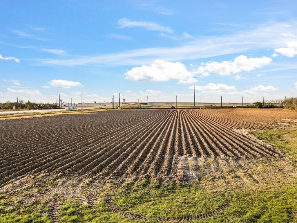 0 Hartledge Road Rosenberg, TX 77471 - Photo 12 of 13 Expansive, flat farmland with neatly plowed rows under a clear blue sky, adjacent to a road. Ideal for agricultural use or development.