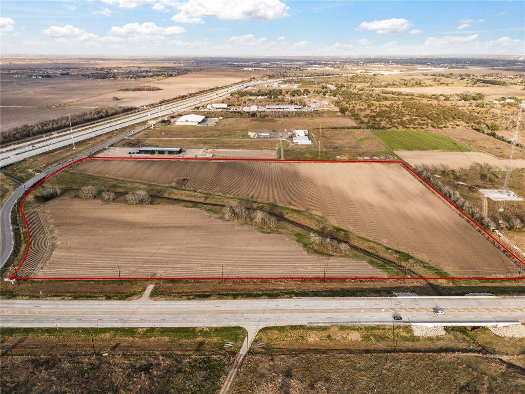 0 Hartledge Road Rosenberg, TX 77471 - Photo 2 of 13 This photo shows a large, open plot of land outlined in red, located near a highway with easy access. The area is mostly flat and clear, ideal for development or agricultural use, with a few nearby structures and expansive rural views in the background.