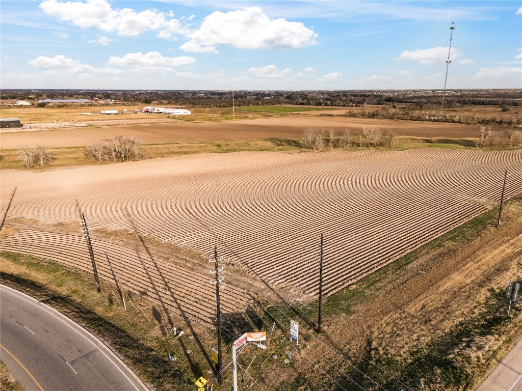 0 Hartledge Road Rosenberg, TX 77471 - Photo 6 of 13 Expansive farmland with neatly plowed fields, bordered by a road and utility poles. The area is open and flat, with a clear sky and distant horizon, ideal for agricultural opportunities.