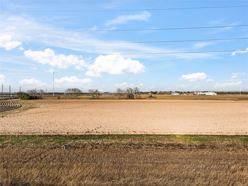 0 Hartledge Road Rosenberg, TX 77471 - Photo 7 of 13 Expansive open land under a blue sky, ideal for development or agriculture, with distant structures and utility lines visible.