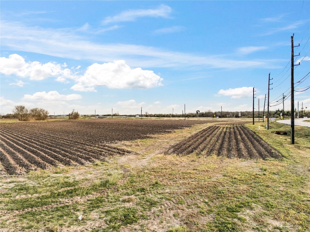 0 Hartledge Road Rosenberg, TX 77471 - Photo 10 of 13 Expansive, flat agricultural land with neatly plowed rows, located alongside a road with utility poles. The area is open and under a bright blue sky, offering potential for development or farming.