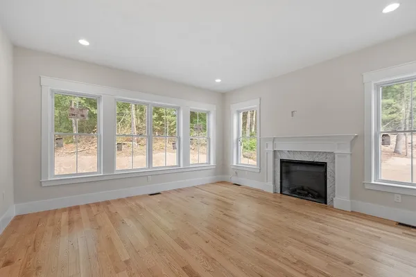 an empty room with wooden floor fireplace and windows