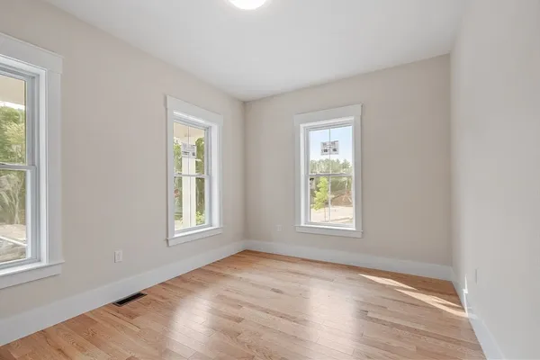 an empty room with wooden floor and windows