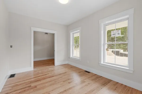 an empty room with wooden floor and windows