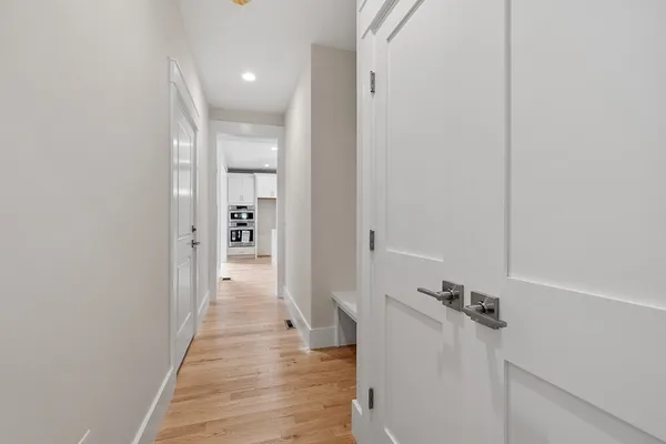 a view of a hallway with wooden floor and a bathroom