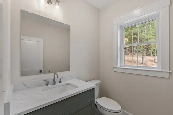 a bathroom with a granite countertop toilet a sink a mirror and a window