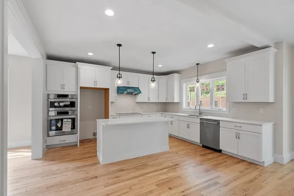 a large kitchen with stainless steel appliances granite countertop a stove and a wooden floors
