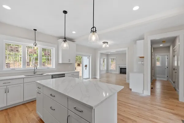 a large kitchen with kitchen island white cabinets and wooden floor