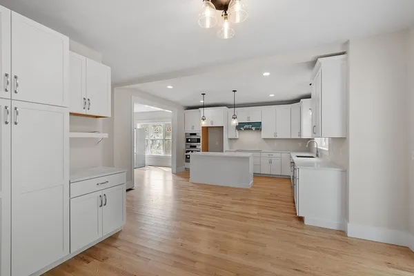 a large kitchen with a center island wooden floor and stainless steel appliances