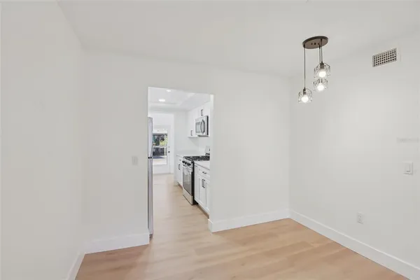 an empty room with wooden floor ceiling fan and windows
