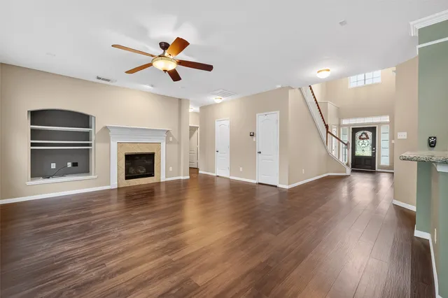 a view of an empty room with wooden floor fireplace and a window