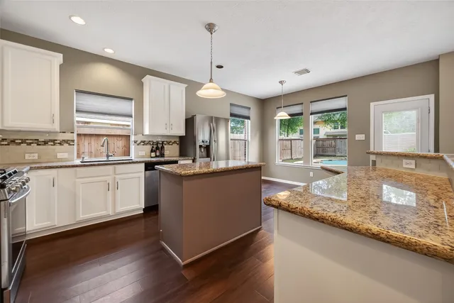 a kitchen with granite countertop kitchen island wooden floor center island and stainless steel appliances