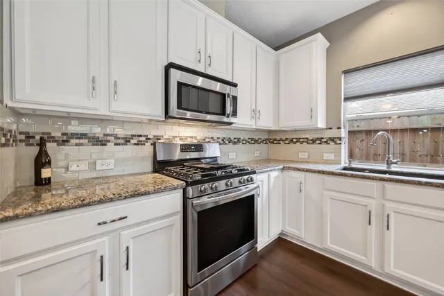 a kitchen with granite countertop white cabinets and appliances