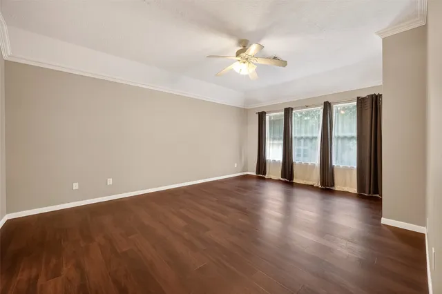 a view of an empty room with wooden floor and window