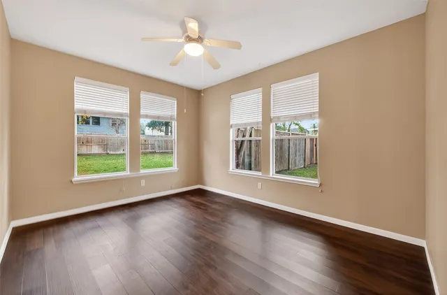 a view of an empty room with a window and wooden floor