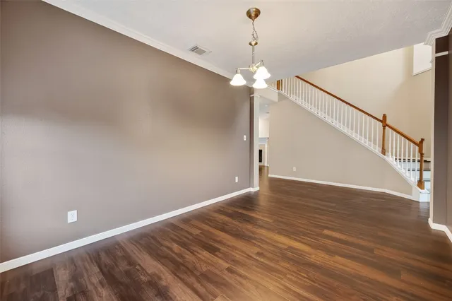 a view of an empty room with wooden floor and a chandelier
