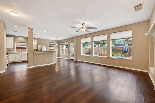 a view of an empty room with a window and wooden floor