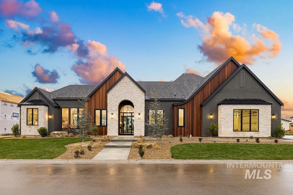 View of front of home with stone siding, a front yard, a standing seam roof, board and batten siding, and a metal roof