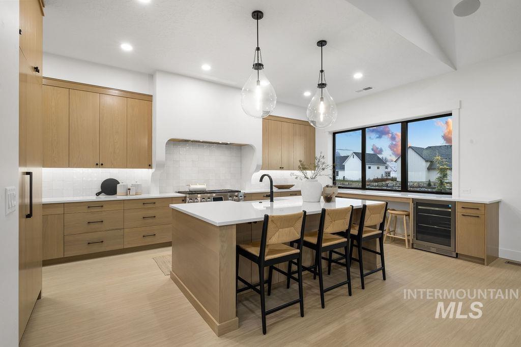 494 Century Avenue Middleton, ID 83644 - Photo 16 of 50 Kitchen featuring modern cabinets, hanging light fixtures, a breakfast bar area, beverage cooler, and a center island with sink