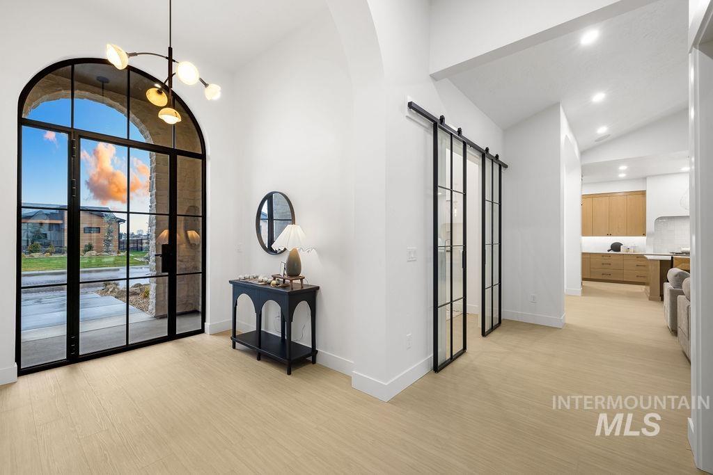 494 Century Avenue Middleton, ID 83644 - Photo 6 of 50 Foyer entrance with a barn door, vaulted ceiling, a chandelier, light wood-style flooring, and arched walkways