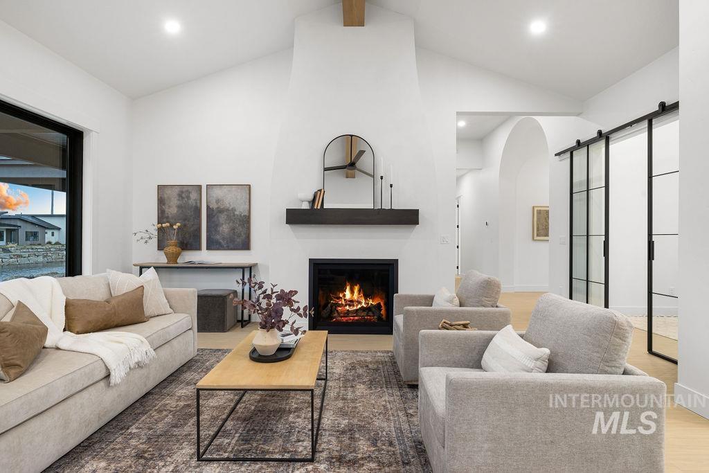 494 Century Avenue Middleton, ID 83644 - Photo 9 of 50 Living room featuring a barn door, a warm lit fireplace, arched walkways, wood finished floors, and recessed lighting