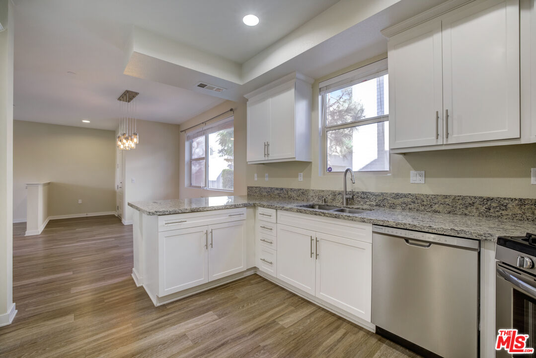 694 Colorado Circle Carson, CA 90745 - Photo 17 of 37 a kitchen with granite countertop white cabinets white appliances a sink and a window
