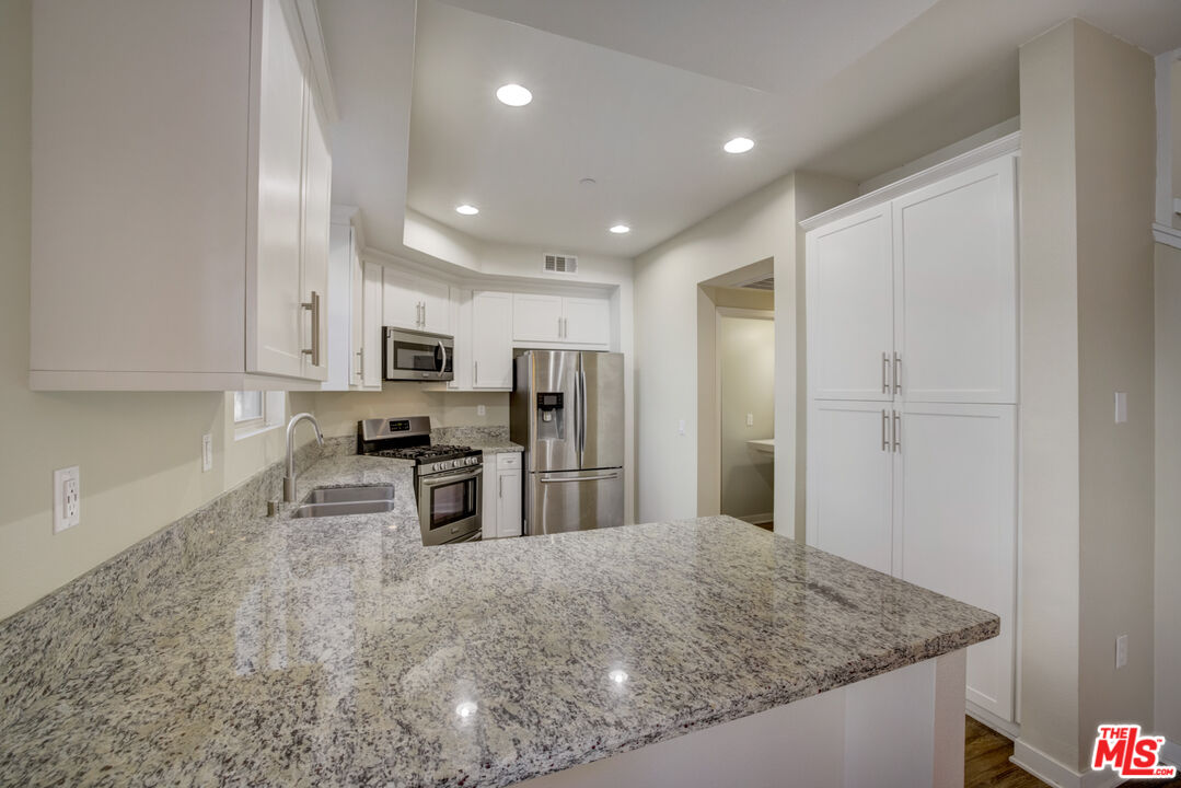 694 Colorado Circle Carson, CA 90745 - Photo 18 of 37 a kitchen with stainless steel appliances granite countertop a sink refrigerator and cabinets