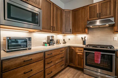 a kitchen with granite countertop wood cabinets stainless steel appliances and a sink