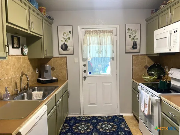 a kitchen with a sink and a stove with wooden floor