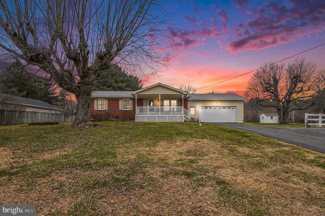 a backyard of a house with large trees and outdoor seating