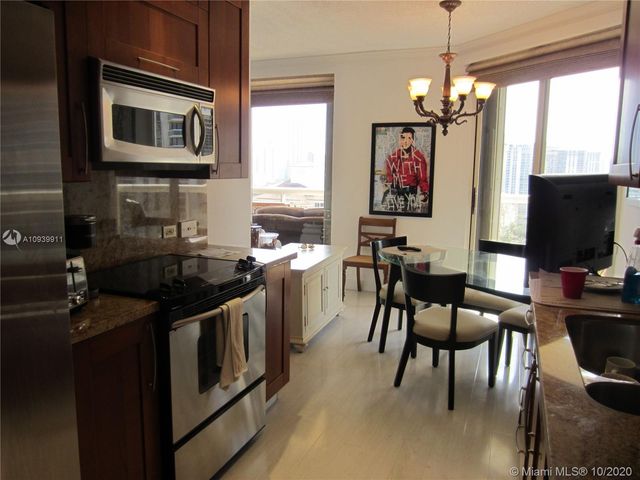 a kitchen with stainless steel appliances granite countertop a stove top oven a sink dishwasher a dining table and chairs with wooden floor