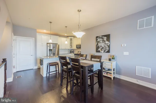 a view of a dining room and livingroom with furniture wooden floor a rug a painting and a chandelier