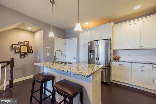 a kitchen with stainless steel appliances granite countertop a table chairs and refrigerator