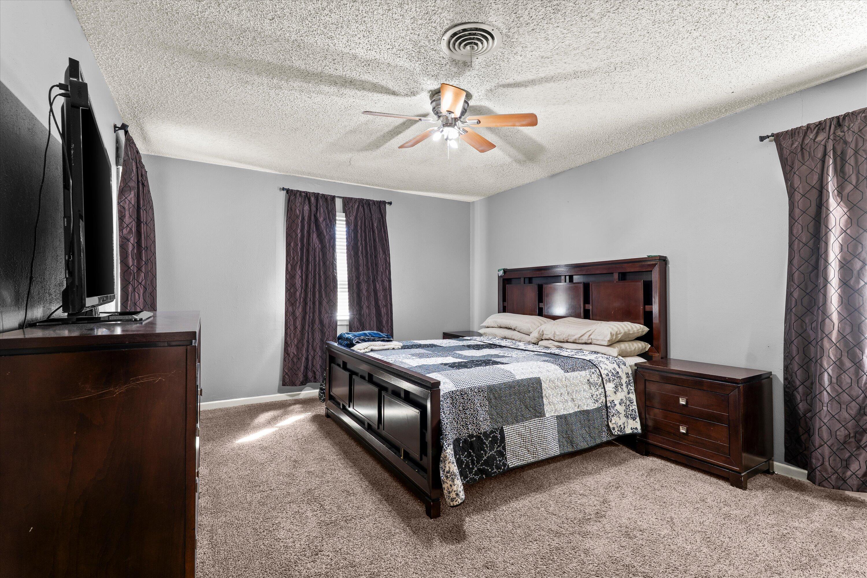 102 3rd Street Plains, TX 79355 - Photo 11 of 29 a bedroom with a bed lamp and a flat tv screen