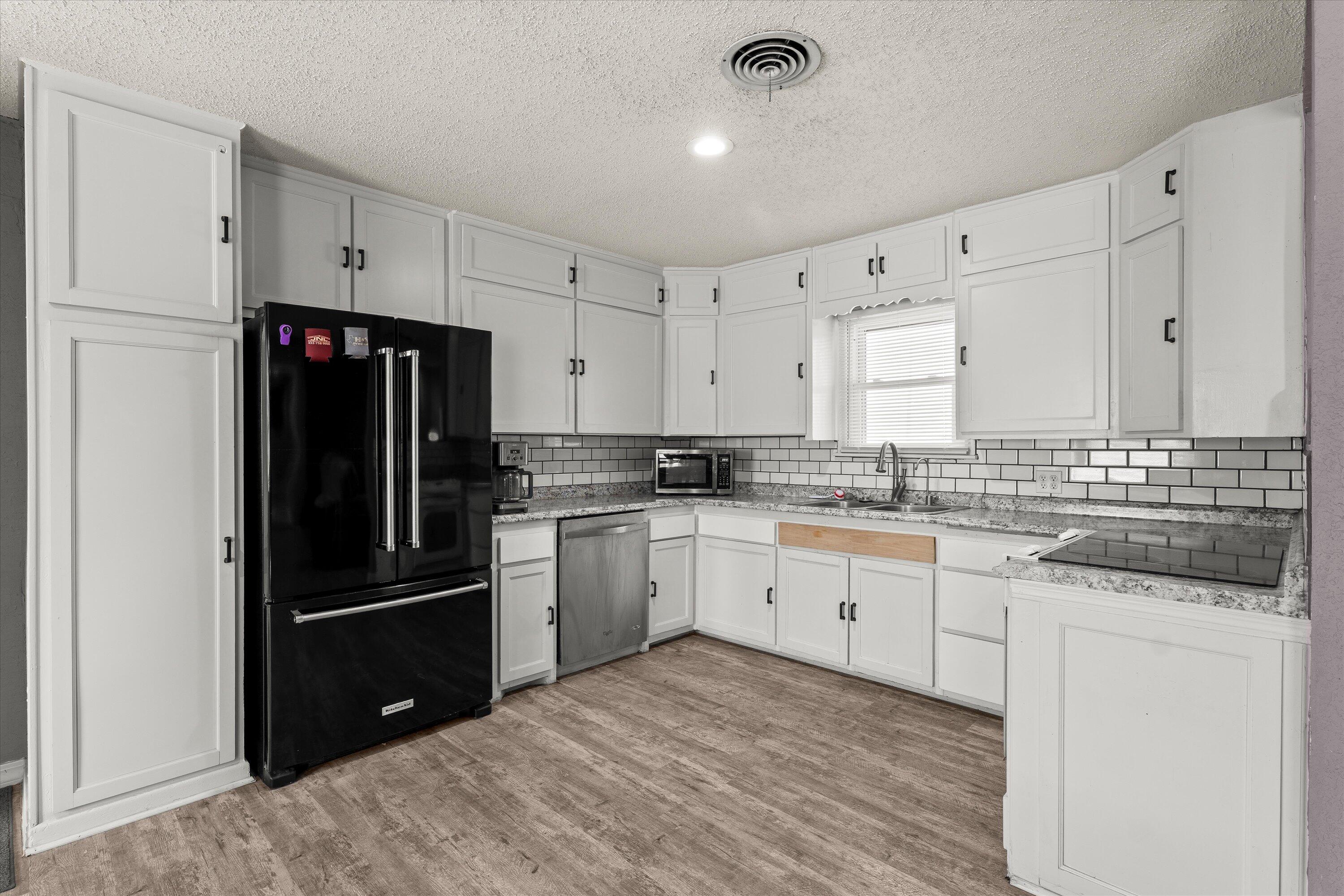 102 3rd Street Plains, TX 79355 - Photo 27 of 29 a kitchen with granite countertop white cabinets and stainless steel appliances