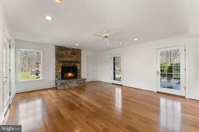 an empty room with windows fireplace and wooden floor