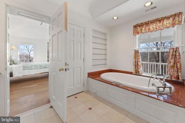 a bathroom with a tub a sink and a large mirror
