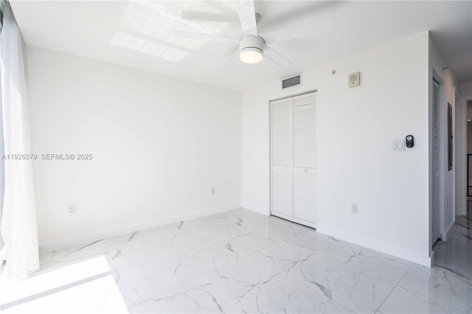 8425 Crespi Boulevard, Unit TH3 Miami Beach, FL 33141 - Photo 22 of 28 an empty room with a ceiling fan and glass door