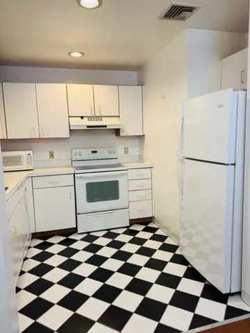 a kitchen with a checkered floor and white cabinets