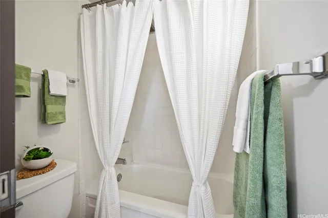 a white bath tub sitting next to a white toilet and curtain