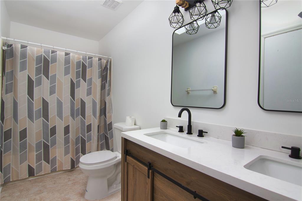 1831 Foxhall Circle Kissimmee, FL 34741 - Photo 11 of 16 a bathroom with a double vanity sink toilet and a mirror