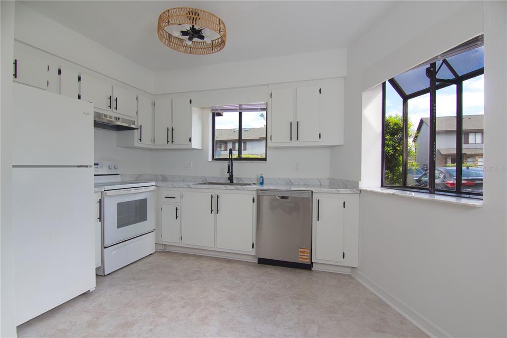 1831 Foxhall Circle Kissimmee, FL 34741 - Photo 3 of 16 a kitchen with granite countertop white cabinets and white appliances
